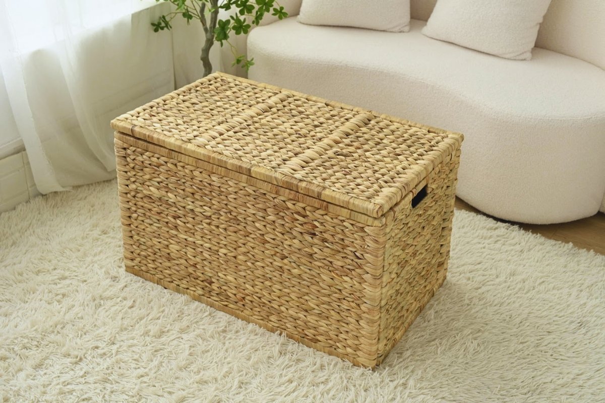 Natural wicker storage trunk used as a minimalist coffee table in a bright living room.